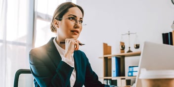 Young woman wearing a business suit in office working on laptop