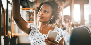 woman riding a bus and listening to a podcast on her phone