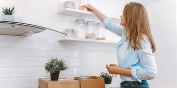 woman unpacking boxes and decorating shelves