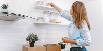 woman unpacking boxes and decorating shelves
