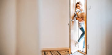 woman entering her front door of her house with groceries