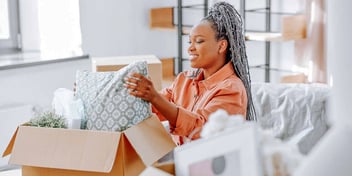 newly divorced woman smiling as she opens a box in her new home