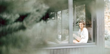 woman sitting in a windowsill of a house