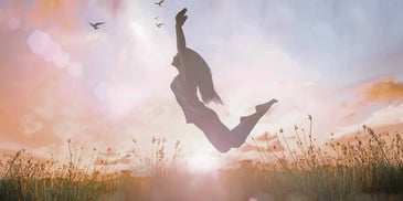 Woman jumps in a field with birds