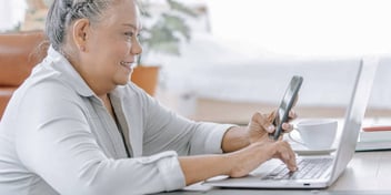 woman looking up information on her smart phone and laptop
