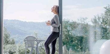 Woman looks outside with tea in hand