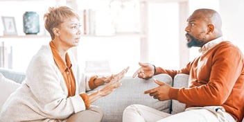 man and woman arguing while sitting facing each other on a couch