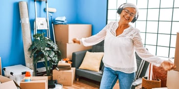 happy single woman dancing and listening to music in her new home