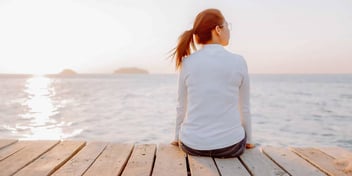 Woman looks out at the water at sunset
