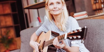 Woman sits on the couch and plays guitar