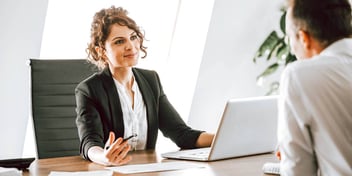 Woman behind desk speaking with man