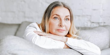 woman thinking alone at home while lounging on a couch