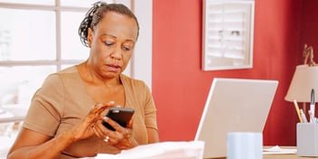 woman looking at calendar on phone while sitting in office
