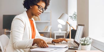 woman reviewing her financial information and paperwork on a computer