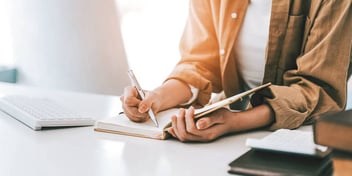 Young woman writing in her notebook on a tabletop