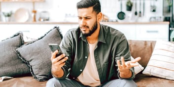 Young man looking at his cell phone in hand with a confused look on his face